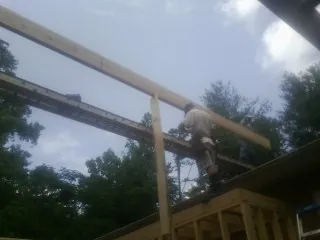 Carpenter setting a ridge beam over a new addition frame — Ice Dam Removal by Roofing Brothers in Baytown