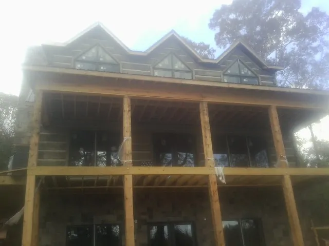 Dormers and porch framing on a large log home under construction — Roof Coating work by our crew in Baytown