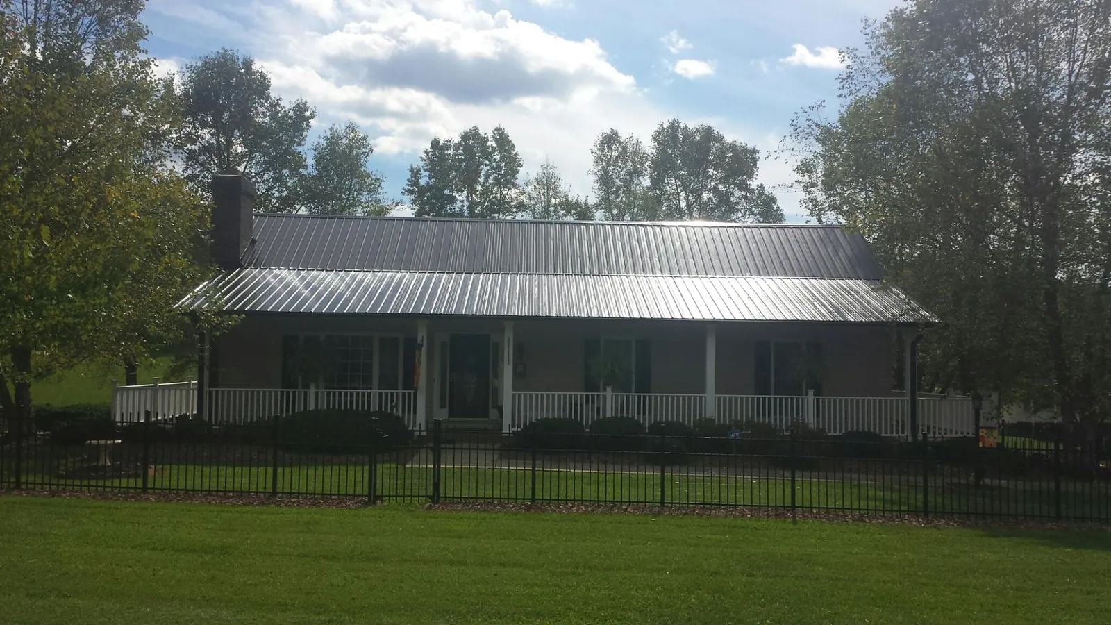 Gray metal roof on a brick ranch with a full width front porch — Gutter Guard Installation work by our crew in Baytown