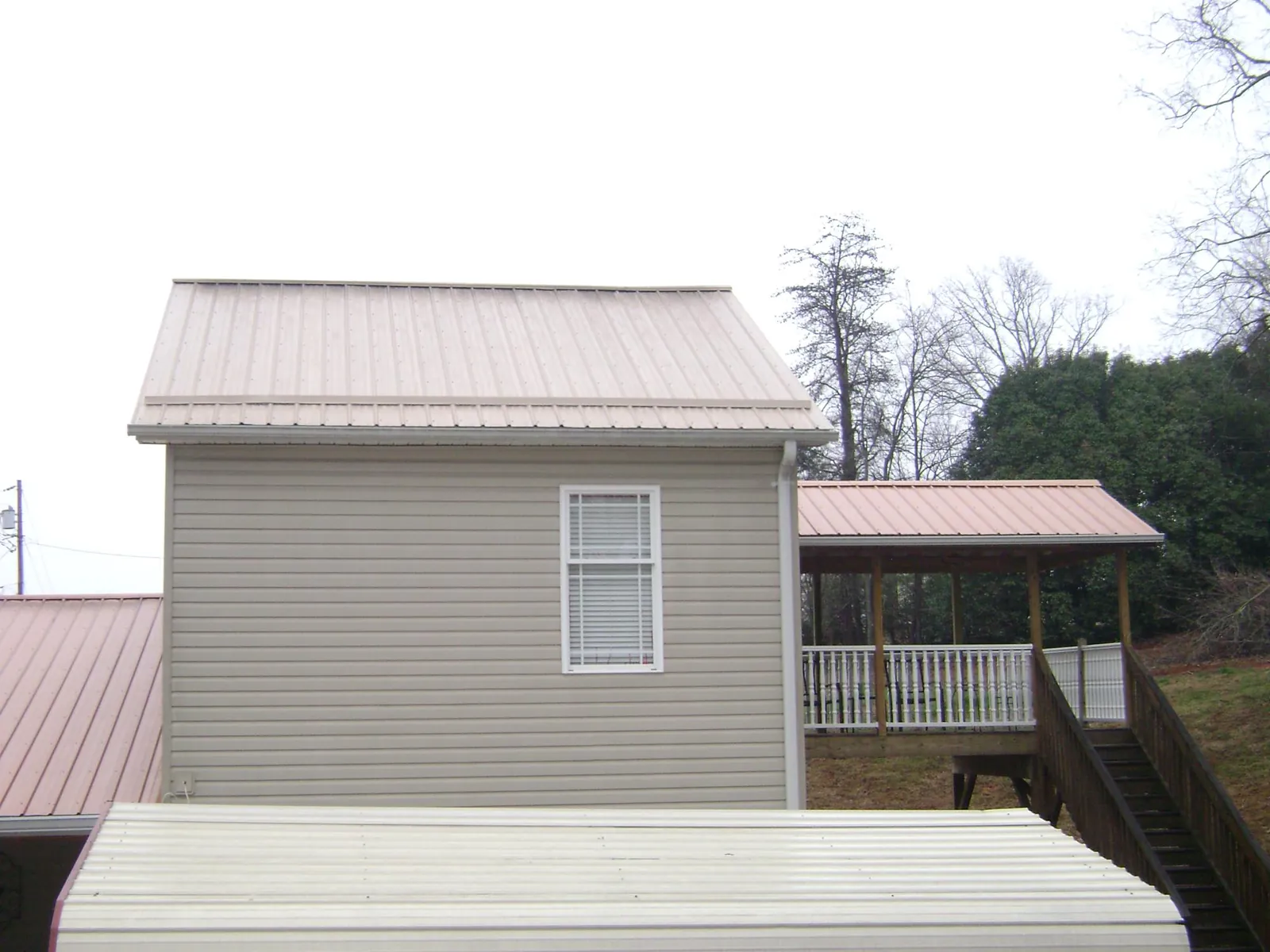 Tan metal roofs on a two story addition and attached porch, from a Roof Replacement job in Baytown