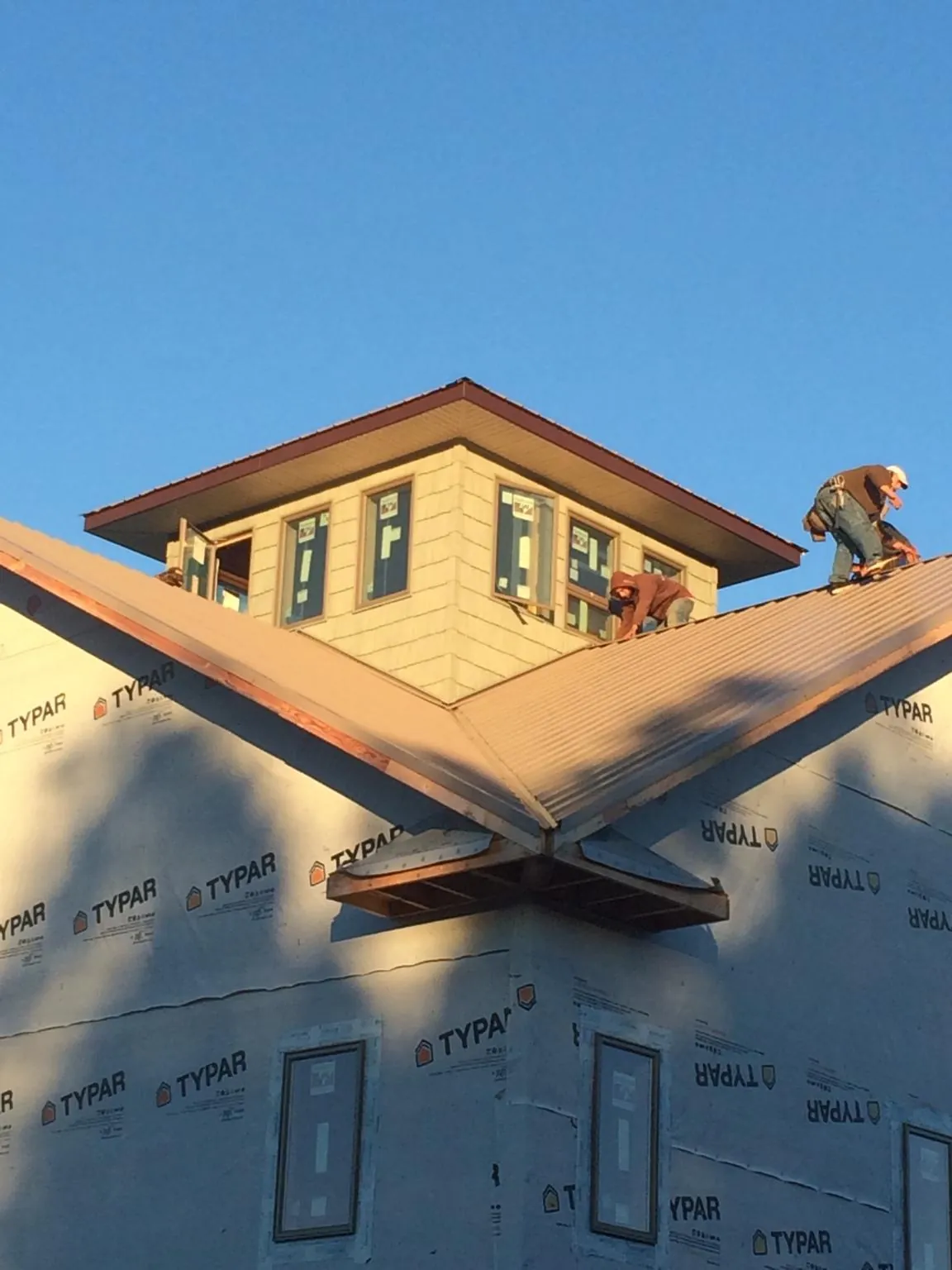 Roofers working around a rooftop cupola on a new metal roof at sunset — Roof Waterproofing in Baytown by Roofing Brothers